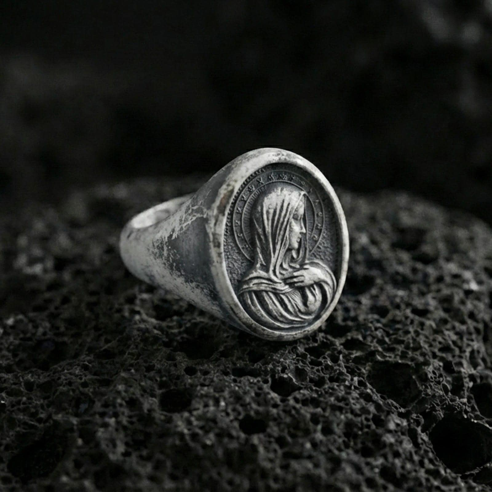 Oxidized sterling silver Virgin Mary signet ring on volcanic rock, oval Marian relief, macro jewelry photo