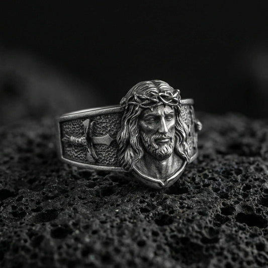 Oxidized sterling silver Jesus Christ ring on volcanic rock, crowned Christ face relief, cross motif band, macro photo