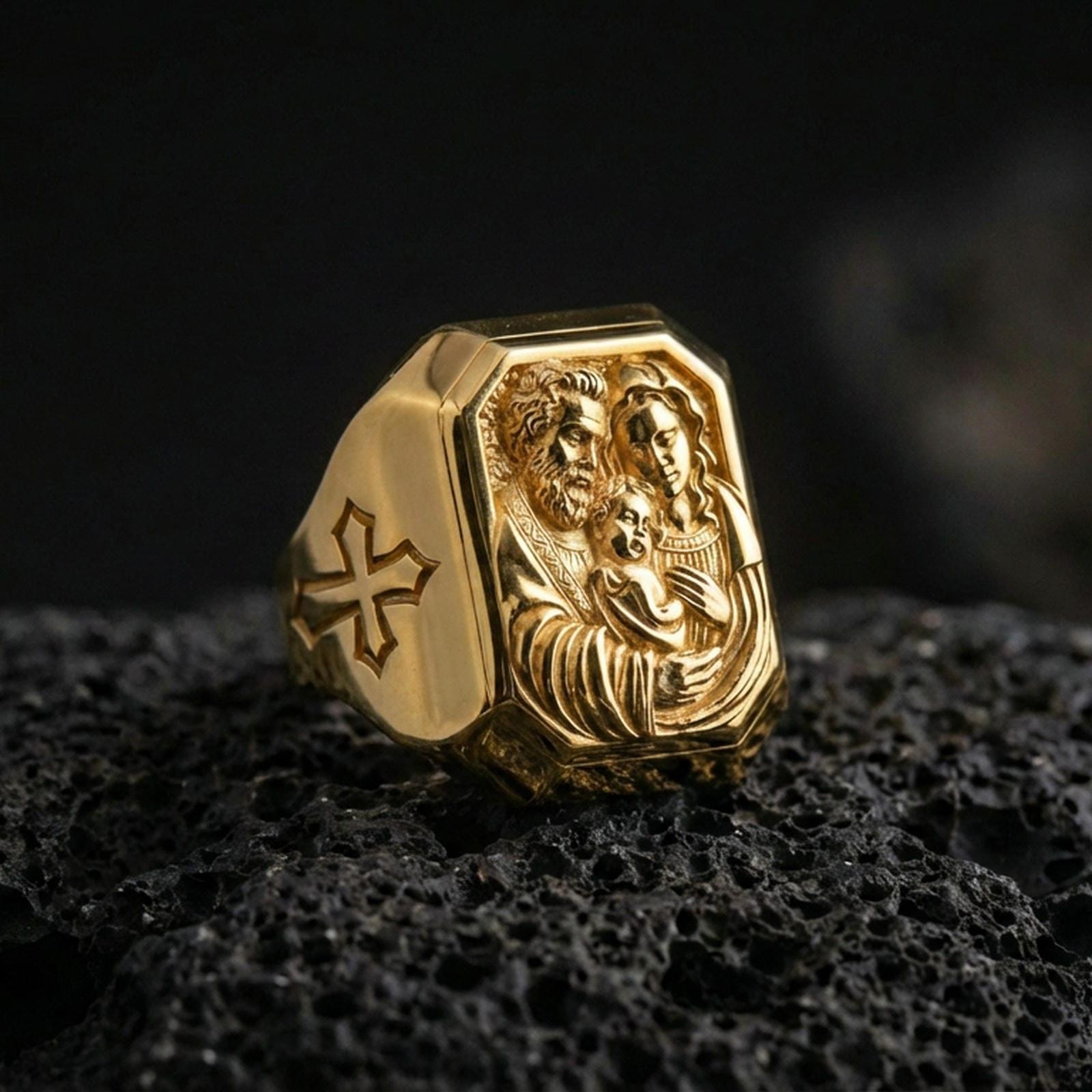 Gold plated Holy Family ring on dark volcanic rock, Saint Joseph Mary Jesus signet ring, cross side motif close-up