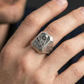 Load image into Gallery viewer, Oxidized sterling silver St Rita ring worn on finger, saint portrait relief, cross shoulder engraving close-up
