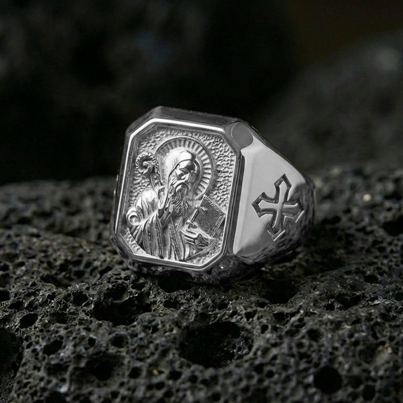 Polished silver Saint Benedict ring on porous volcanic stone, halo relief carving, Christian protection jewelry