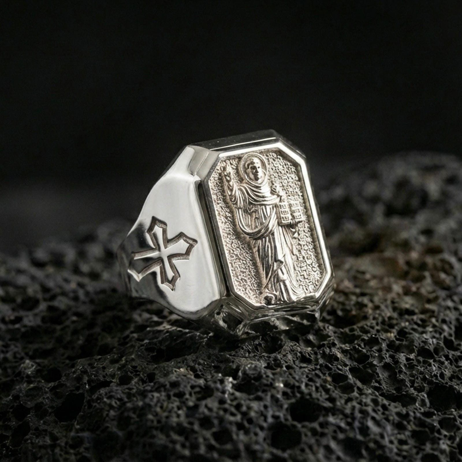 Polished silver St Dominic ring on porous volcanic stone, detailed saint portrait carving, Catholic signet jewelry