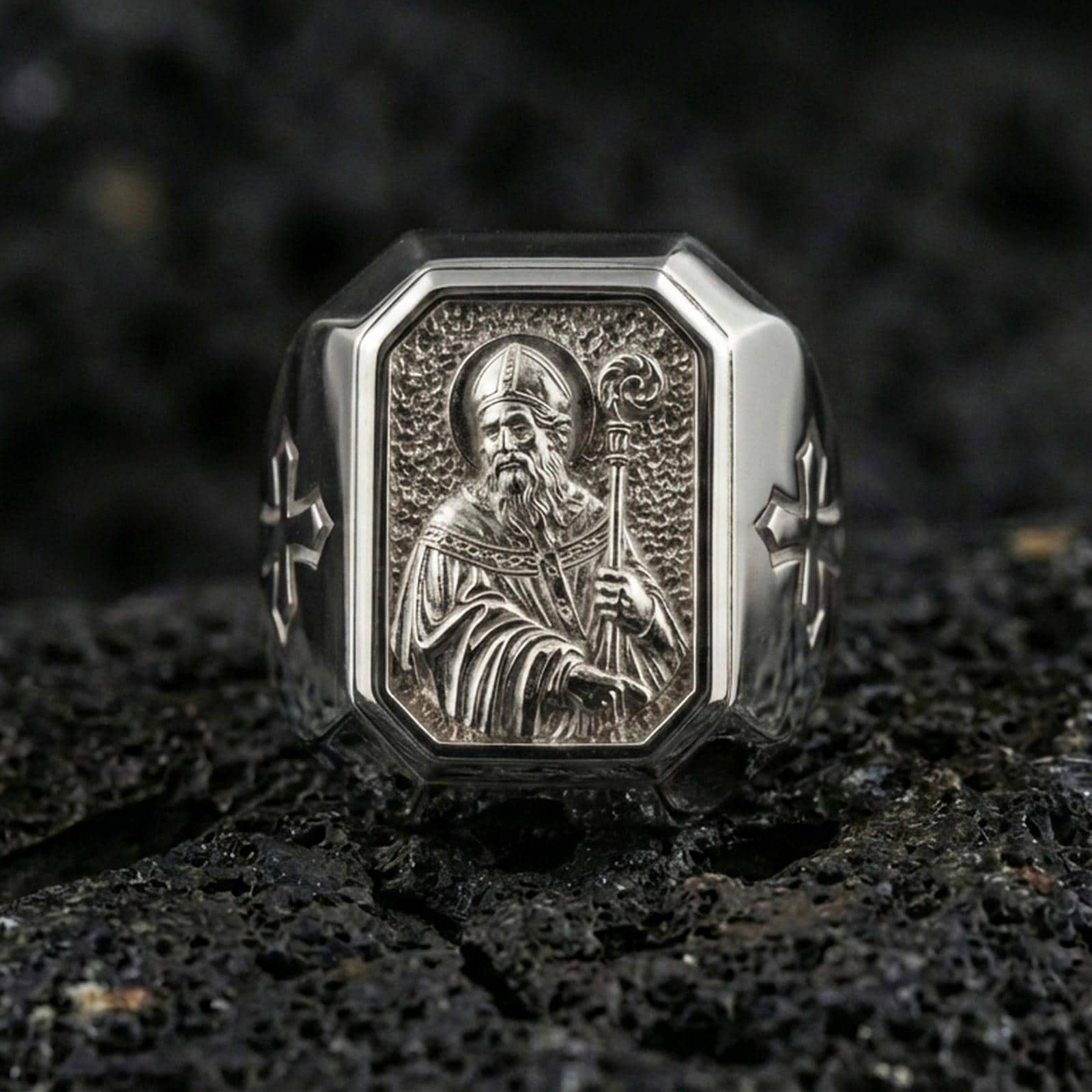 Polished silver St Patrick ring on porous volcanic stone, detailed saint portrait carving, Catholic signet jewelry