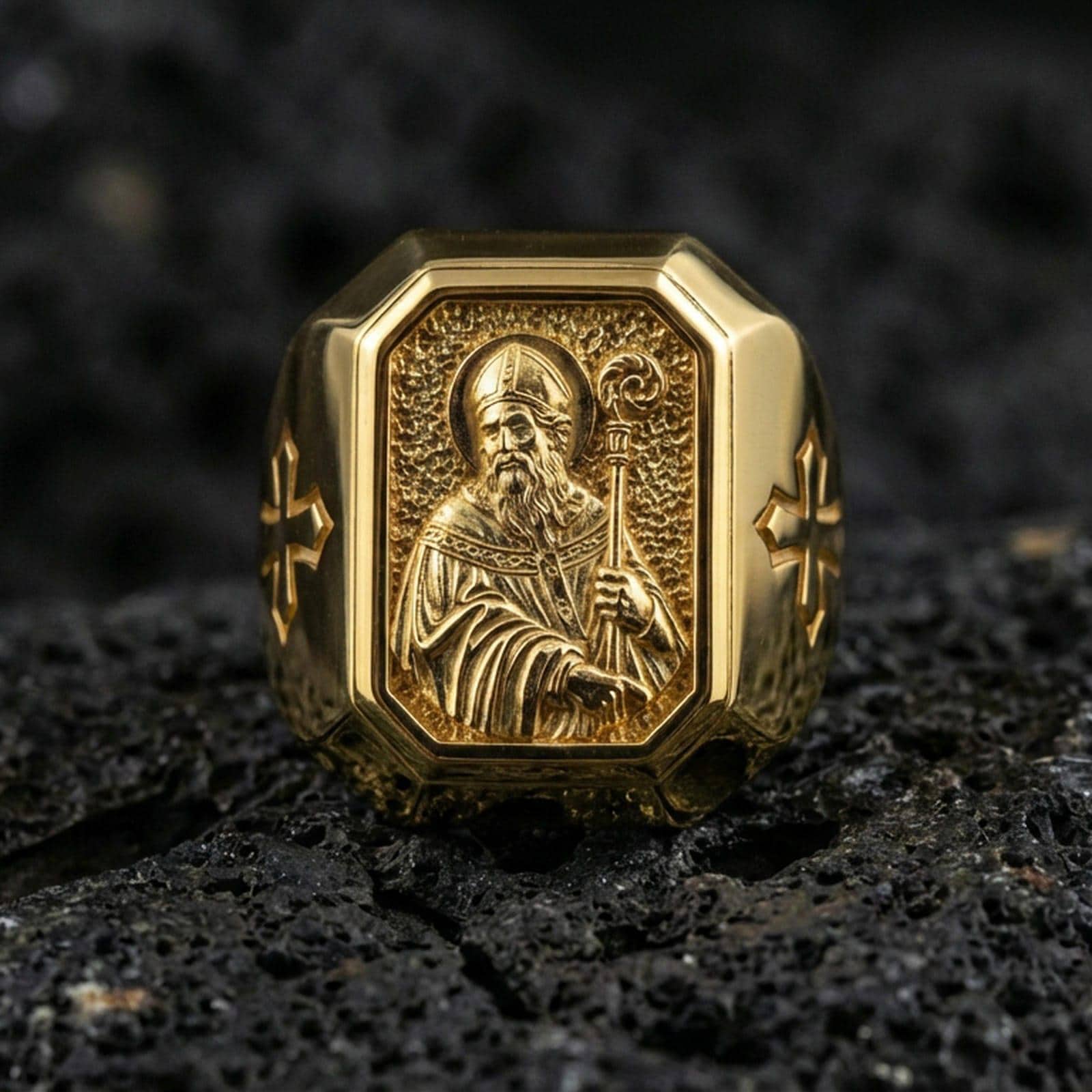 Gold plated St Patrick signet ring on dark volcanic rock, bishop staff relief, cross shoulder detail close-up