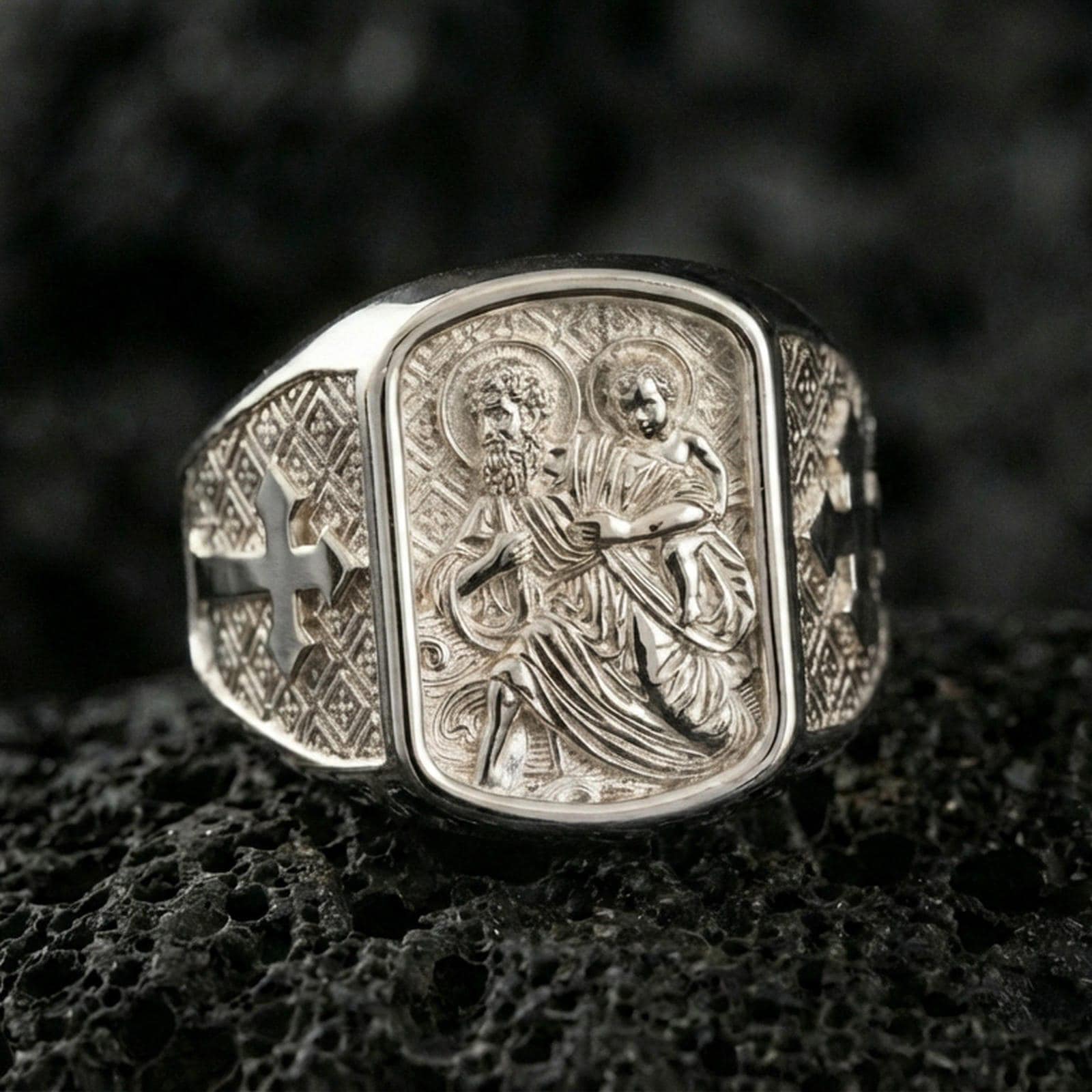 Polished silver Saint Christopher signet ring on porous volcanic stone, traveler protector icon relief, detailed engraving close-up