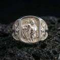 Load image into Gallery viewer, Polished silver St Sebastian signet ring on porous volcanic stone, detailed saint engraving, Christian cross shoulders close-up
