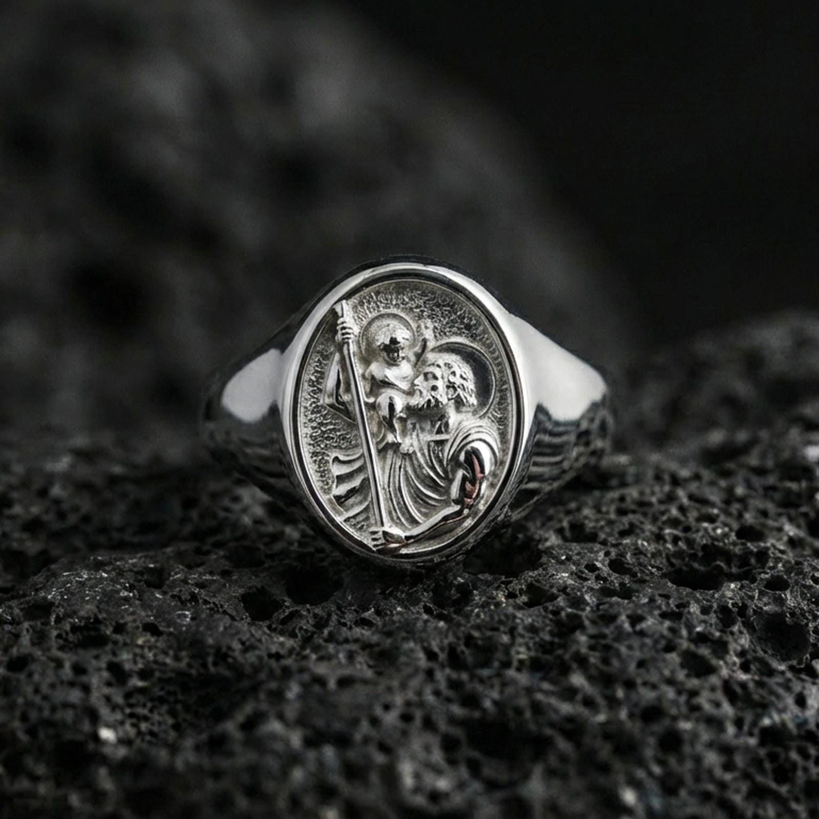 Polished silver St Christopher ring on porous volcanic stone, saint carrying child engraving, religious travel protection jewelry