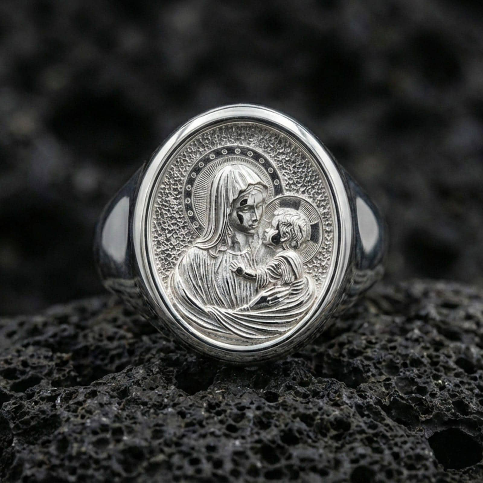 Polished silver Virgin Mary ring on porous volcanic stone, Sacred Child halo detail, Christian faith signet ring