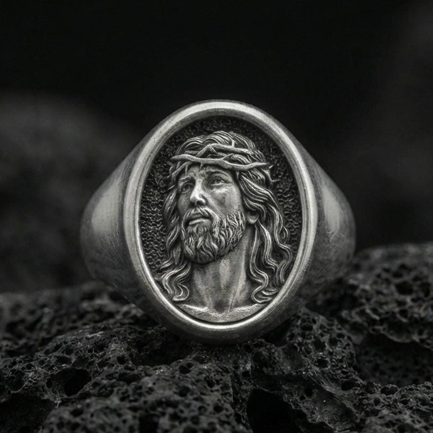 Oxidized 925 sterling silver Jesus signet ring on volcanic rock, crown of thorns Savior portrait closeup
