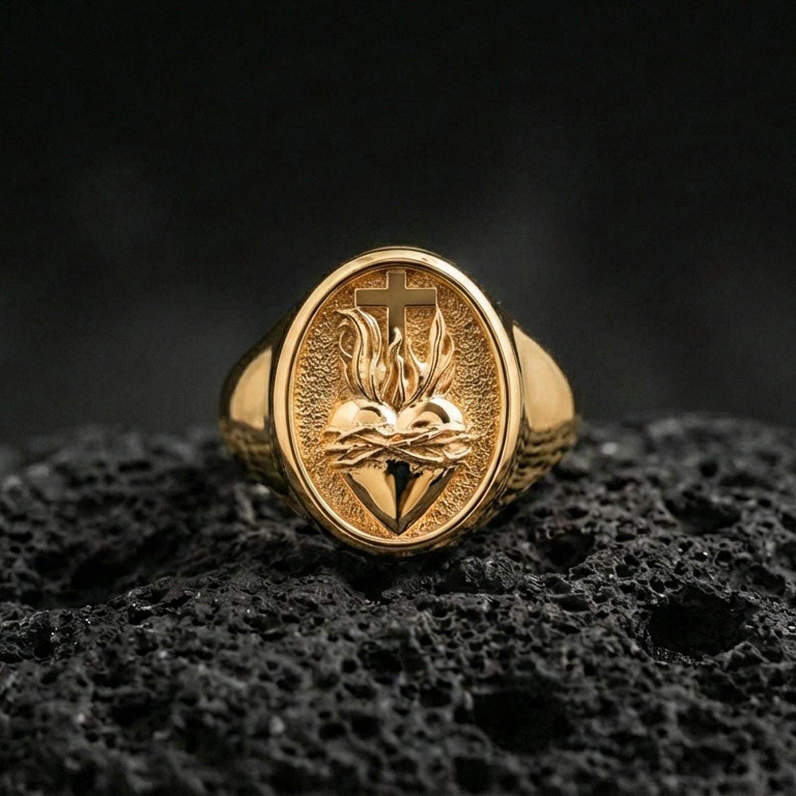 Gold plated Sacred Heart signet ring on dark volcanic rock, cross and flame heart motif, religious jewelry gift