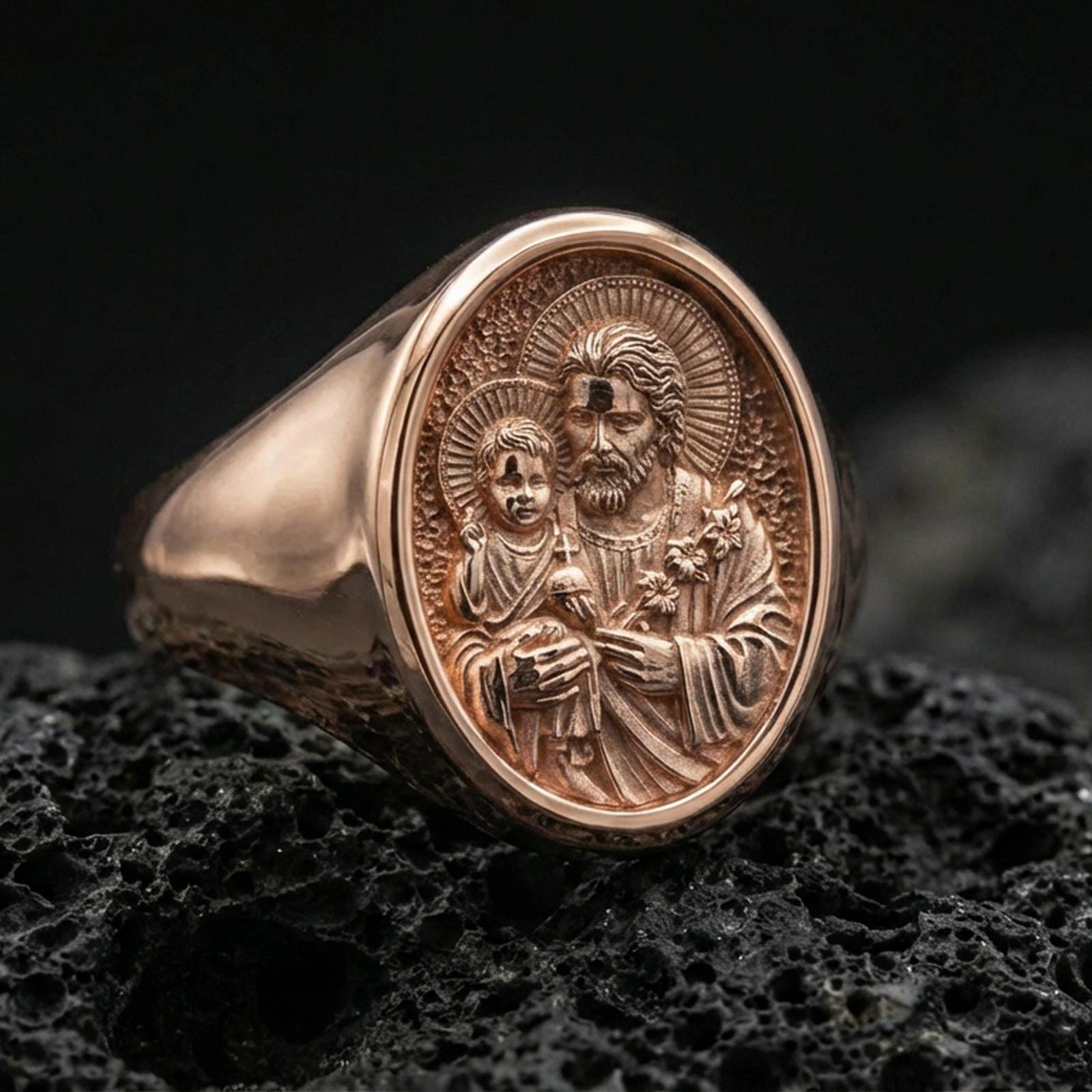 Rose gold plated Saint Joseph ring on volcanic stone, Holy Family relief signet macro detail