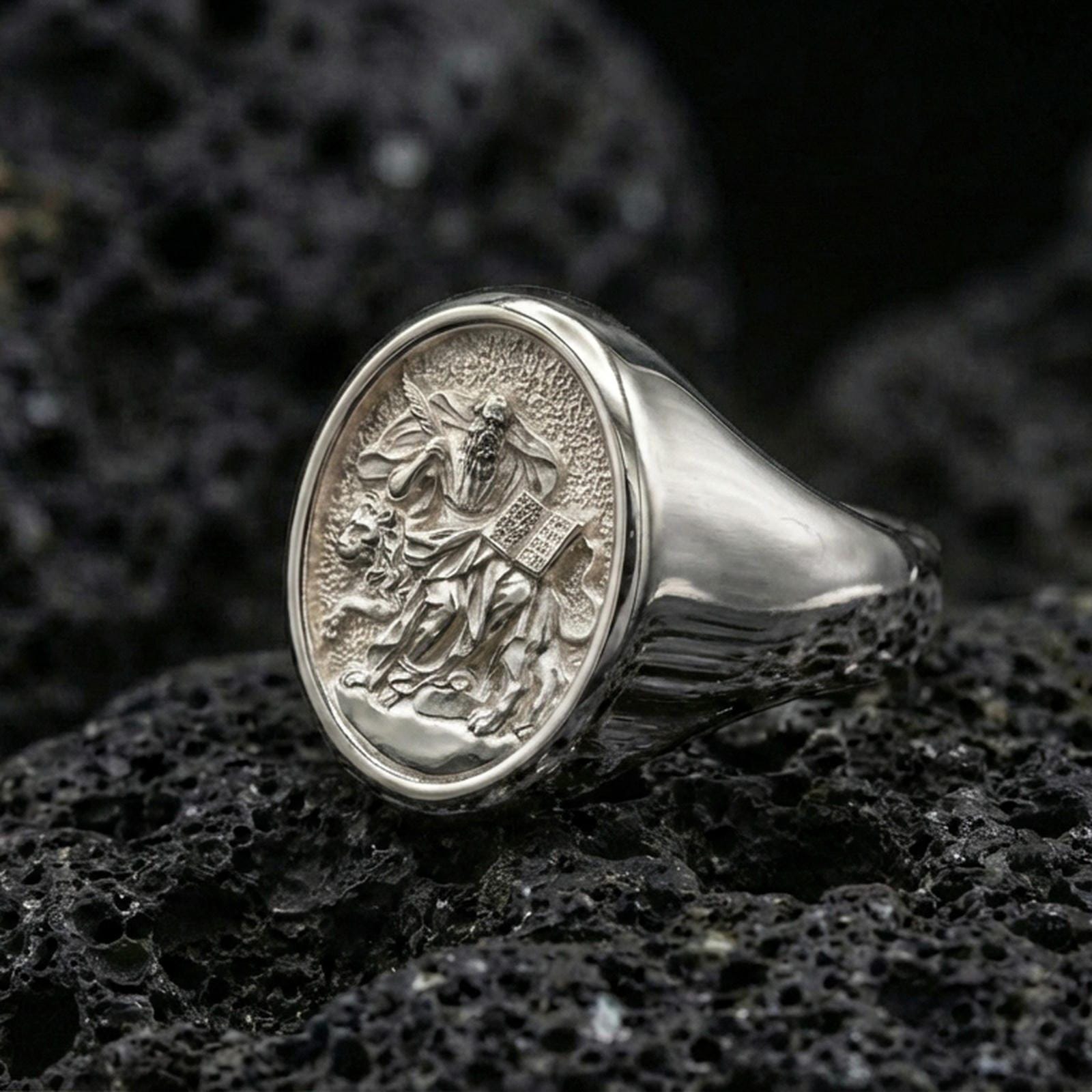 Polished silver Saint Mark ring on volcanic stone, evangelist symbol signet macro closeup