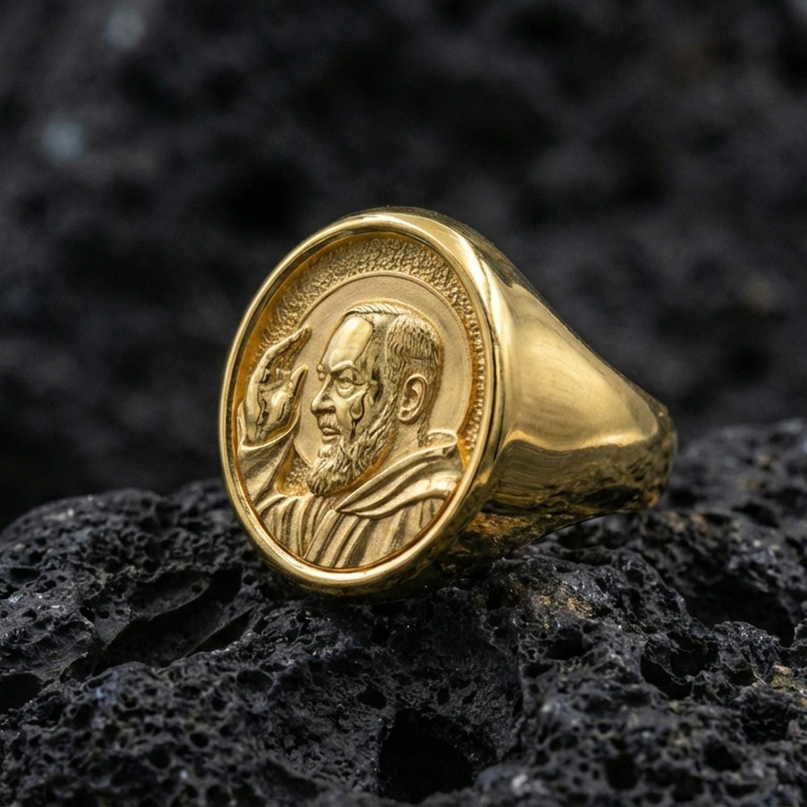 Gold plated Padre Pio signet ring on dark volcanic rock, saint portrait design, Catholic faith jewelry gift