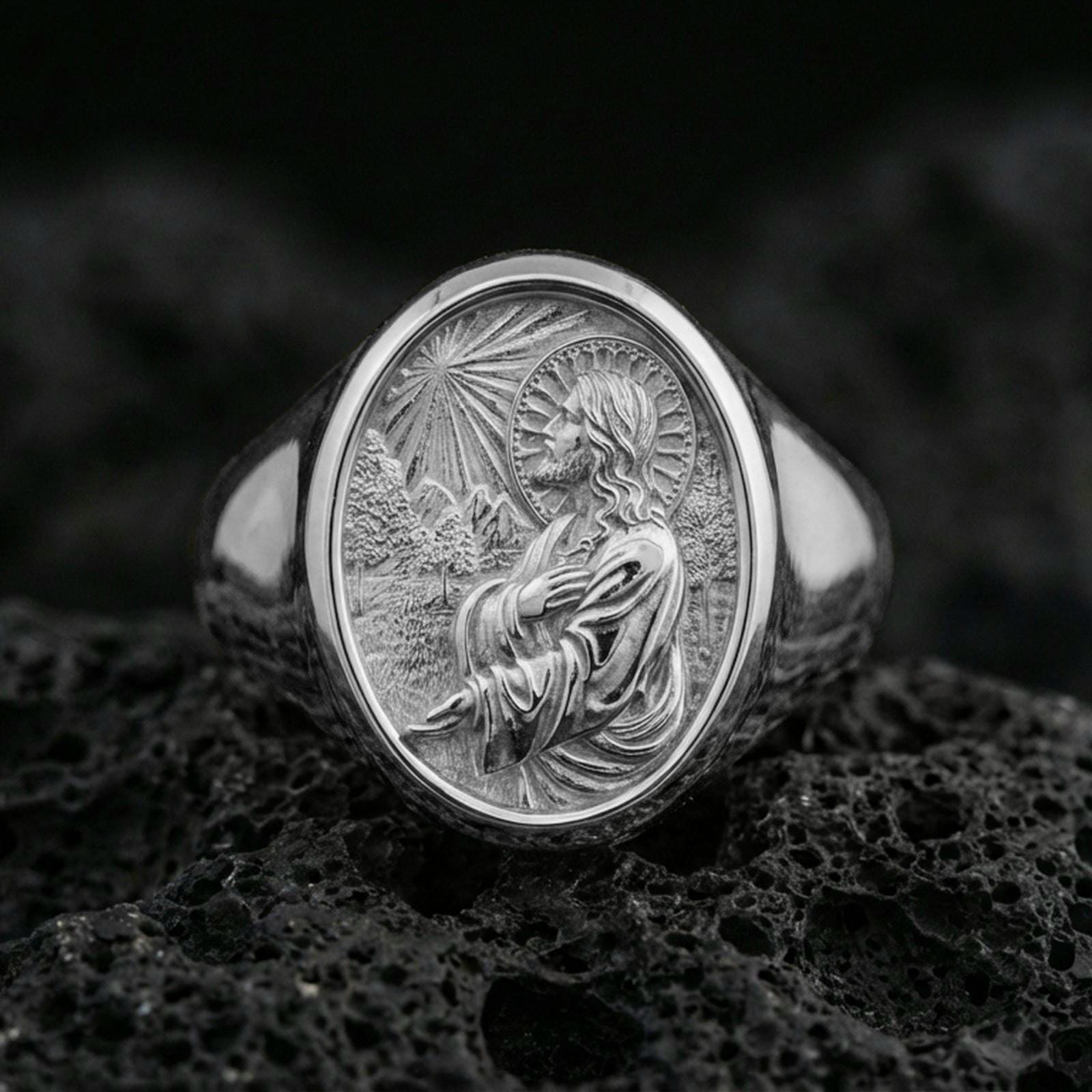 Polished silver Jesus Christ ring on volcanic stone, side profile Christ engraving closeup