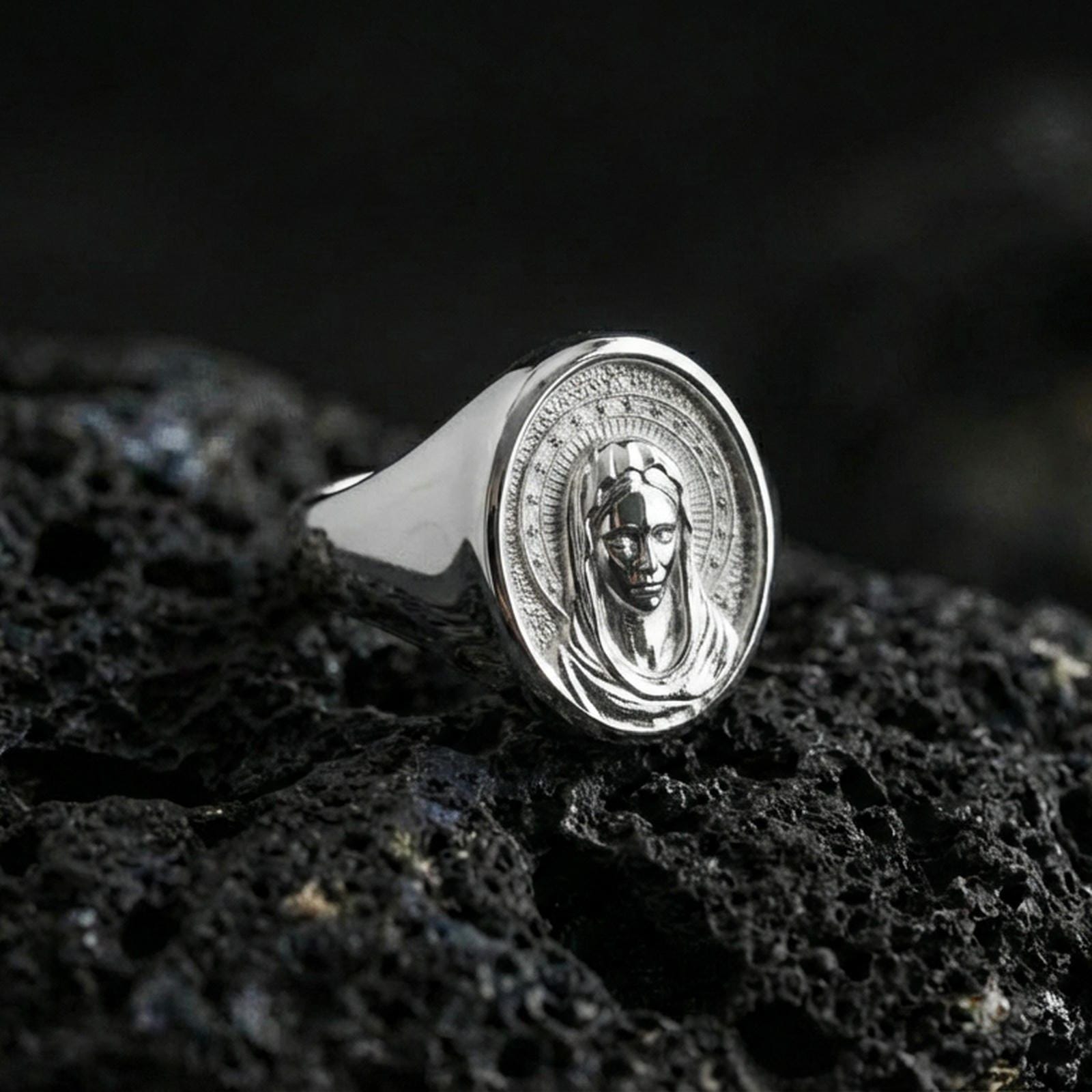 Polished silver Virgin Mary ring on porous volcanic stone, detailed Madonna portrait engraving, religious signet ring