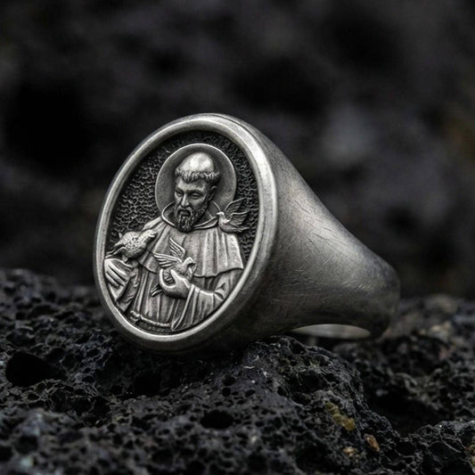 Oxidized sterling silver St Francis signet ring on volcanic rock, detailed saint relief portrait