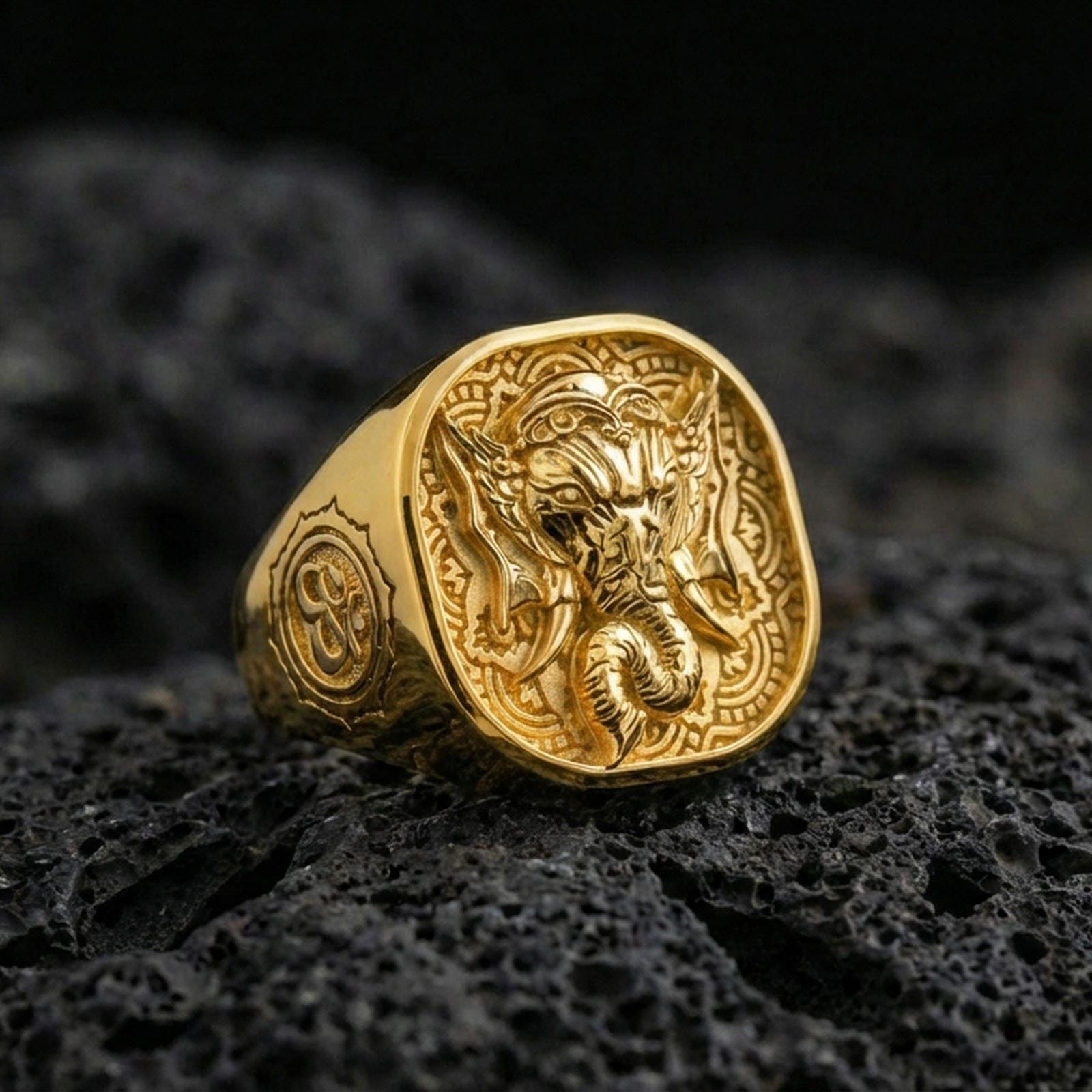Gold plated Lord Ganesha signet ring on dark volcanic rock, elephant god motif, Hindu protection jewelry