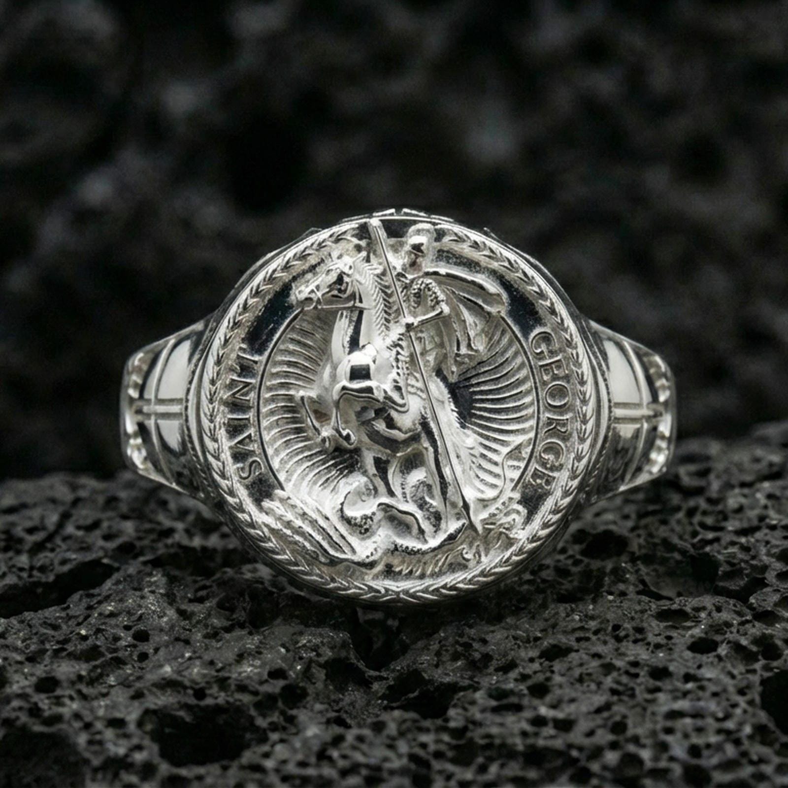 Polished silver St. George dragon signet ring on porous volcanic stone, Saint George emblem, medieval warrior style