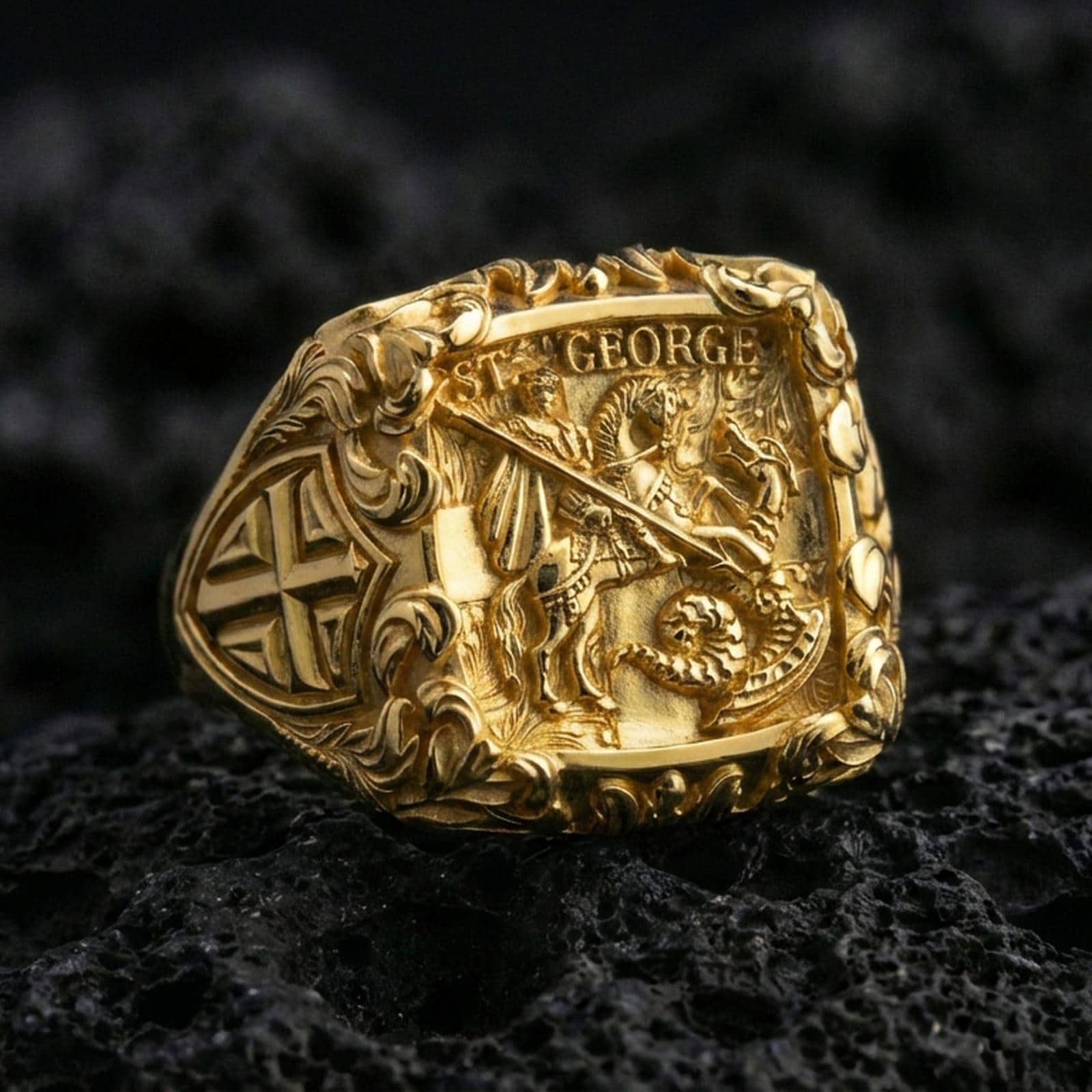 Gold plated sterling silver St George defeating dragon ring on dark volcanic rock, medieval warrior signet with cross motif