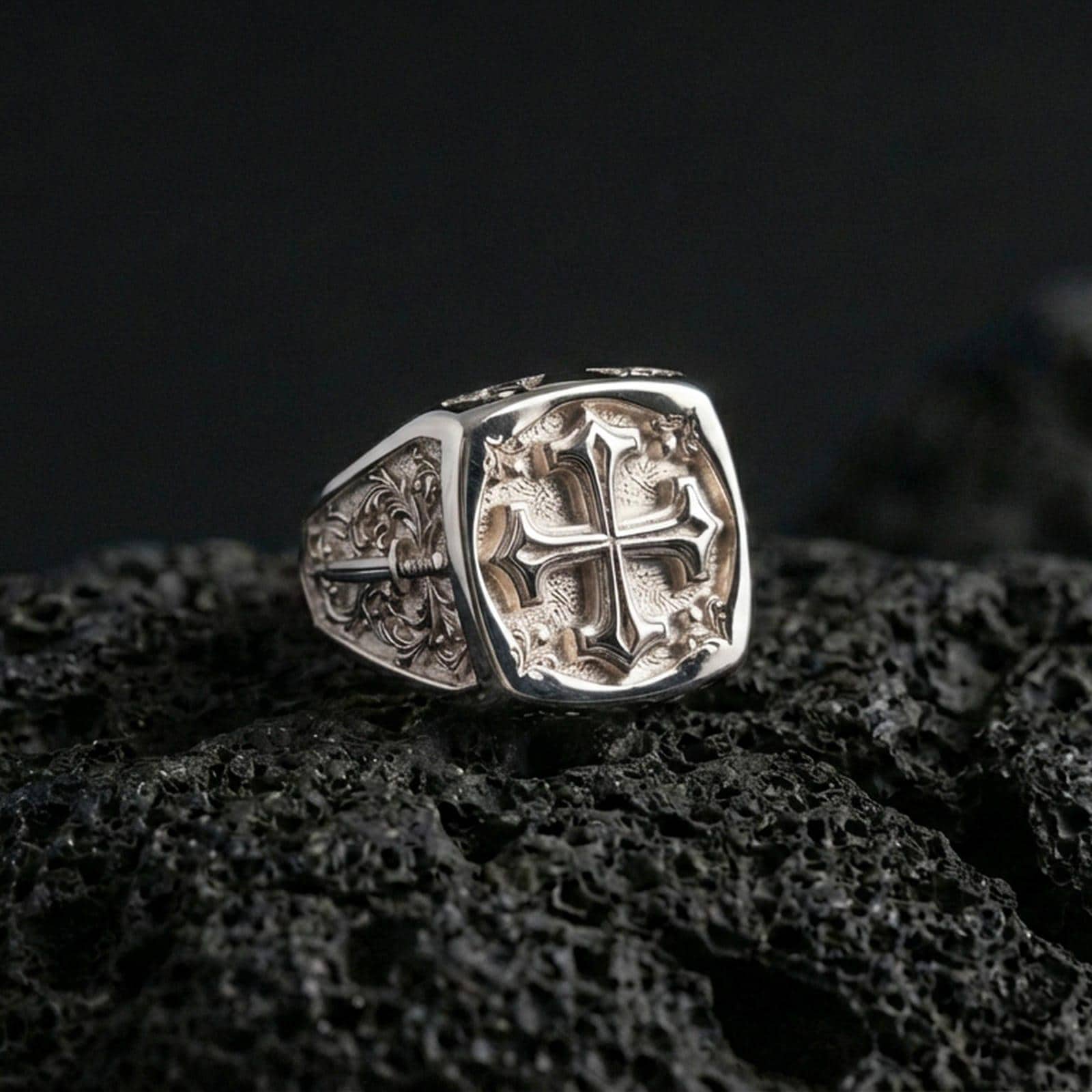 Polished silver crusader cross ring on porous volcanic stone, bold Christian symbol signet, engraved details