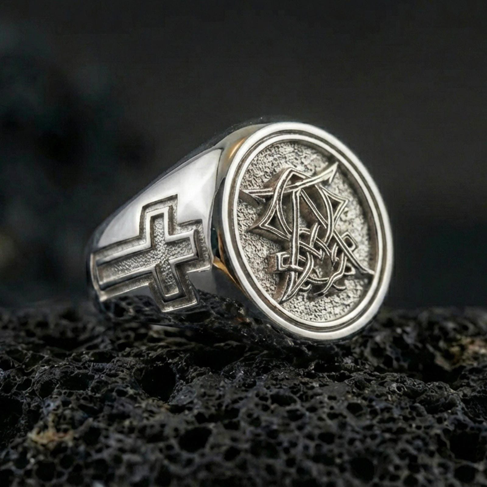 Polished silver Christian monogram signet ring on porous volcanic stone, raised monogram seal and side cross detail