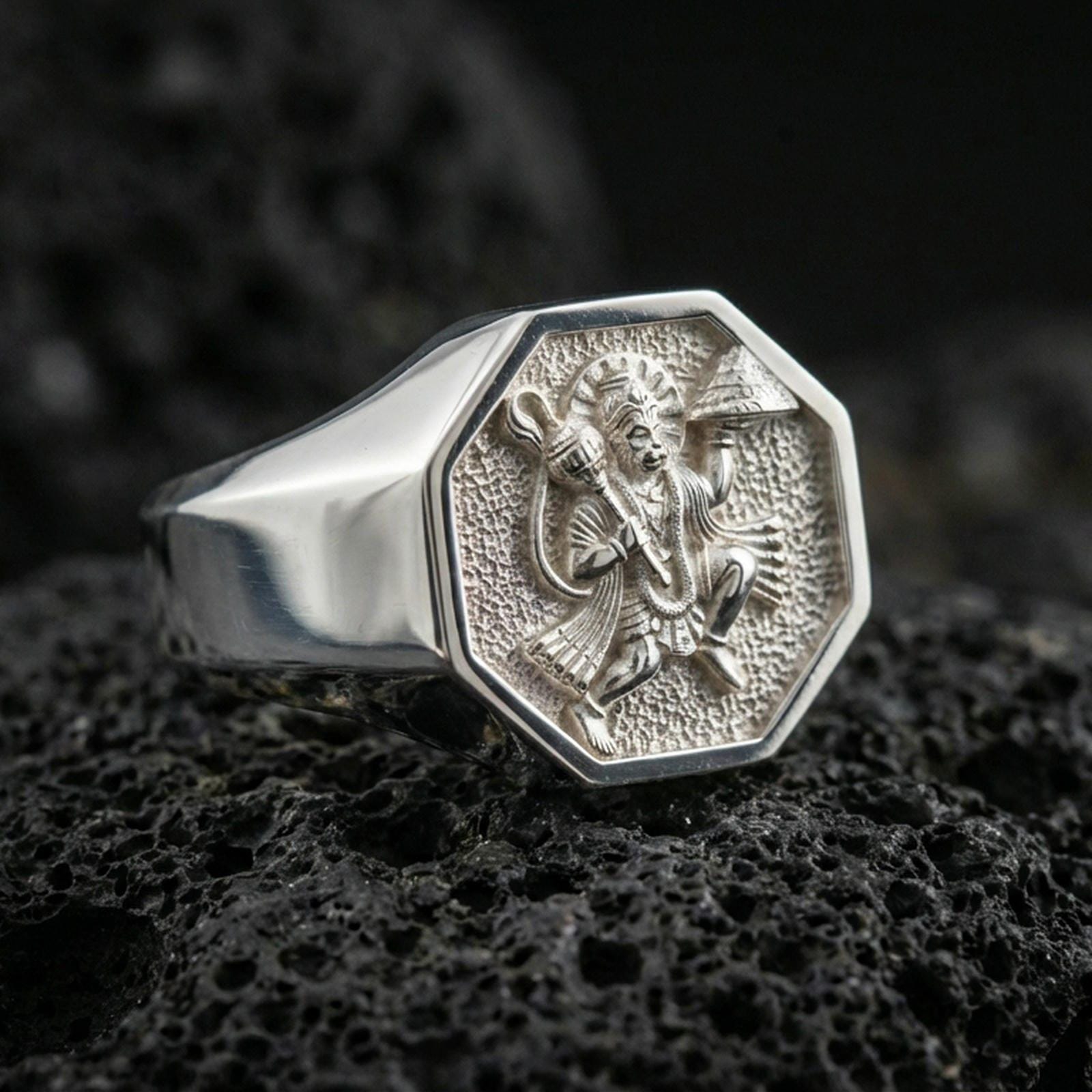 Polished silver Hanuman signet ring on porous volcanic stone, octagonal signet face with engraved Hindu deity and clean band