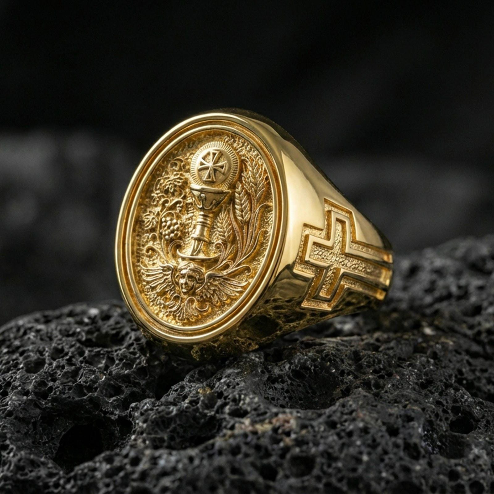 Gold plated Holy Eucharist signet ring on dark volcanic rock, chalice and host relief with wheat and vine motif, cross on band