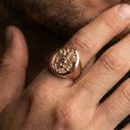 Load image into Gallery viewer, Rose gold plated spiritual signet ring worn on finger, oval signet face with multi-faced deity relief and premium handmade look
