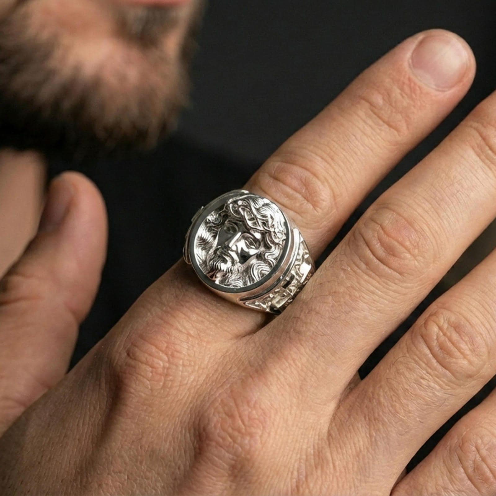 Polished silver Jesus Christ ring worn on finger, round portrait signet with clean reflective bezel and bold band