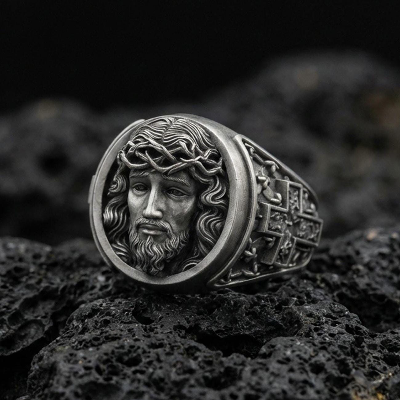 Oxidized 925 sterling silver Jesus ring on volcanic rock, crown of thorns portrait relief with deep antiqued shadows