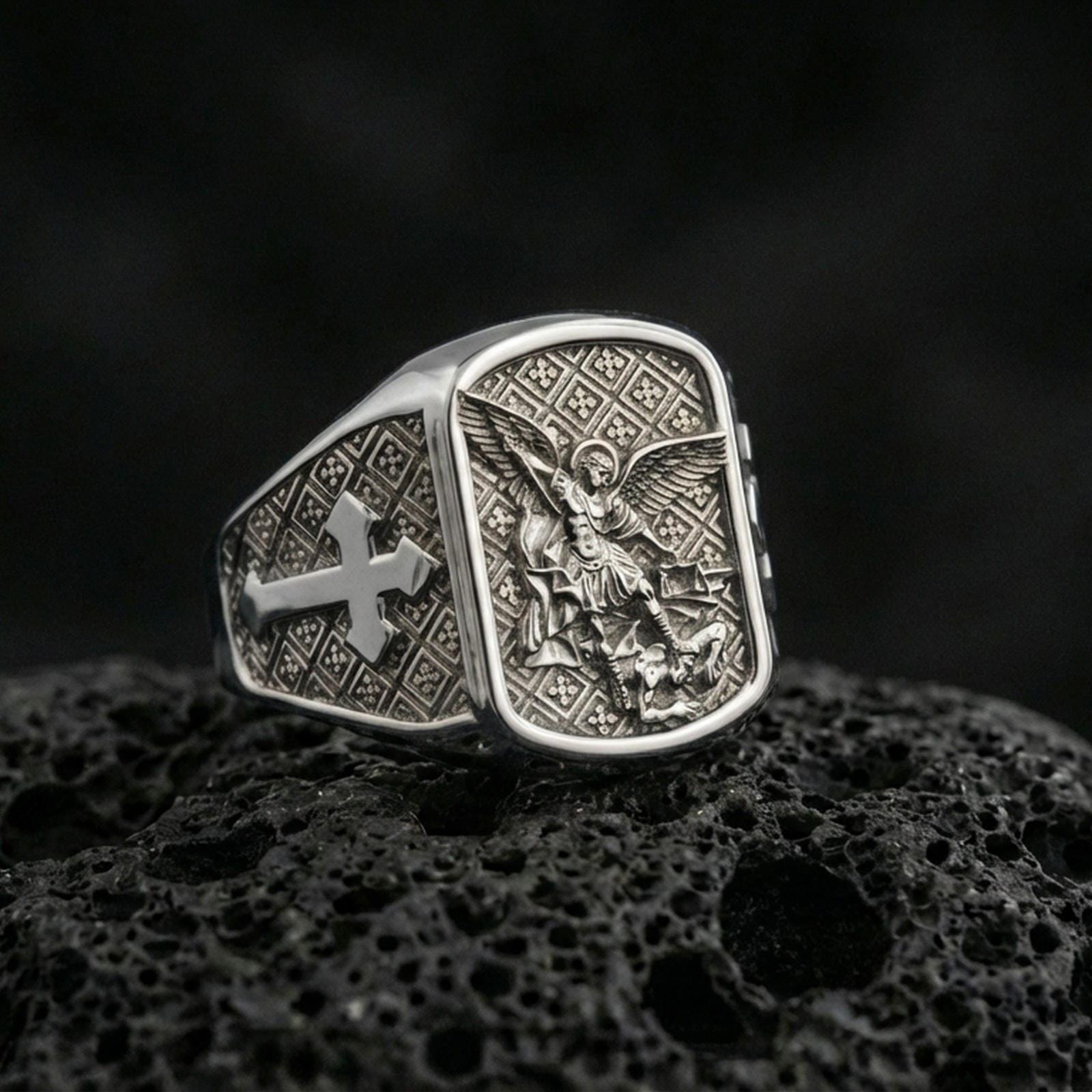 Polished silver Archangel Michael signet ring on porous volcanic stone, detailed battle relief and clean bezel shine