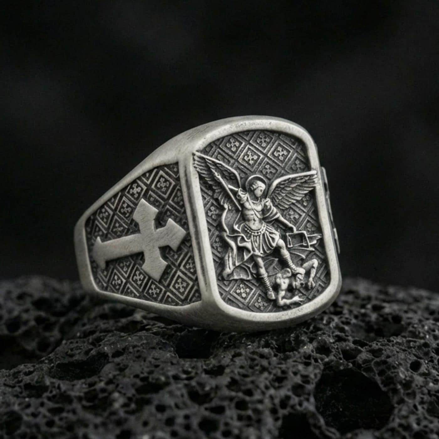 Oxidized 925 sterling silver Archangel Michael ring on volcanic rock, Michael slaying demon relief with cross side motif