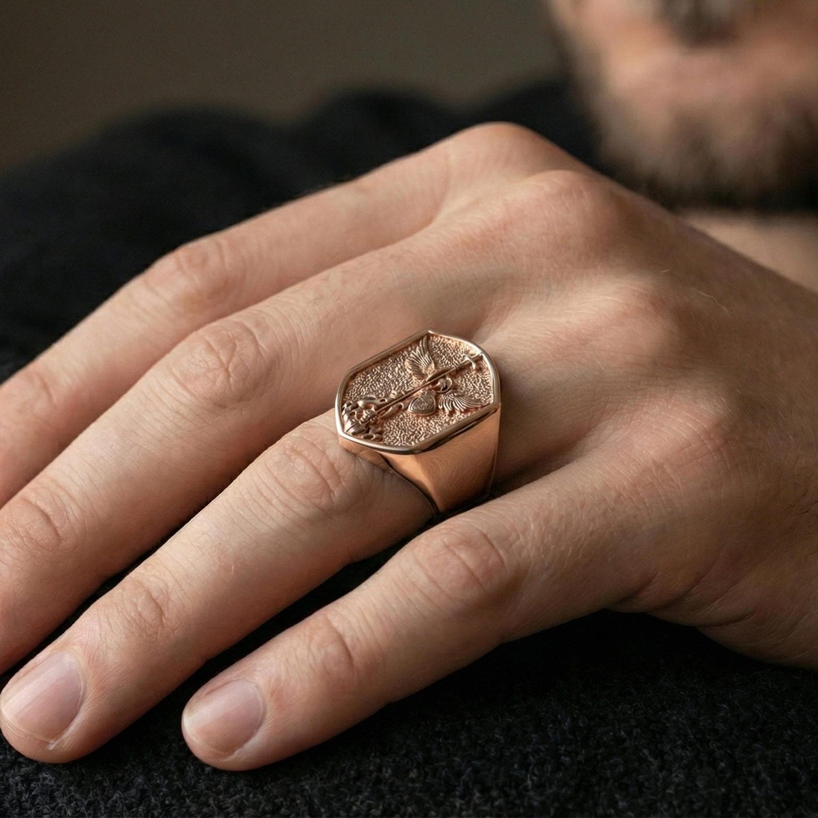 Rose gold plated Saint Michael signet ring worn on finger, raised border shield face with saint warrior motif