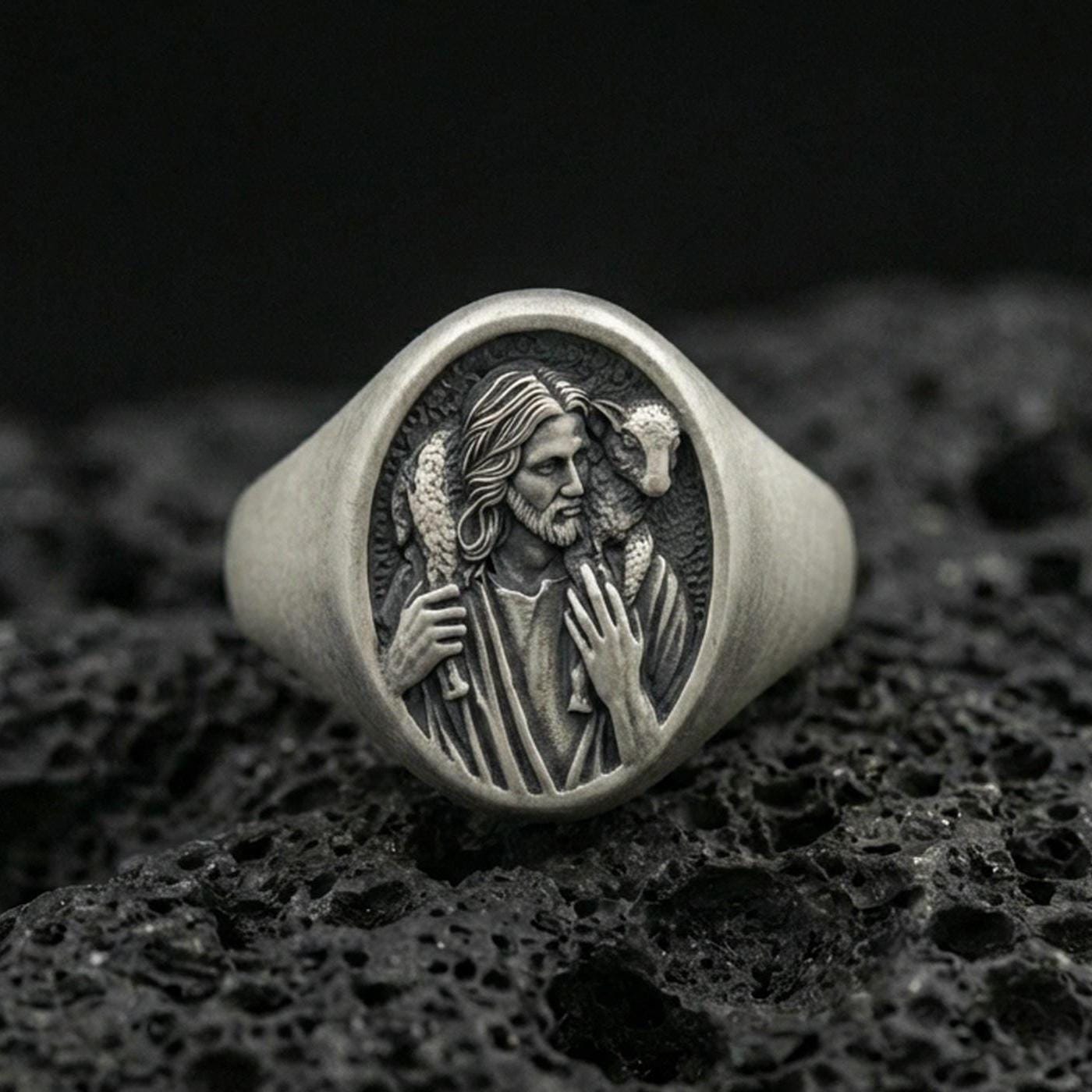 Oxidized 925 sterling silver Jesus Good Shepherd signet ring on volcanic rock, Christ carrying lamb relief face