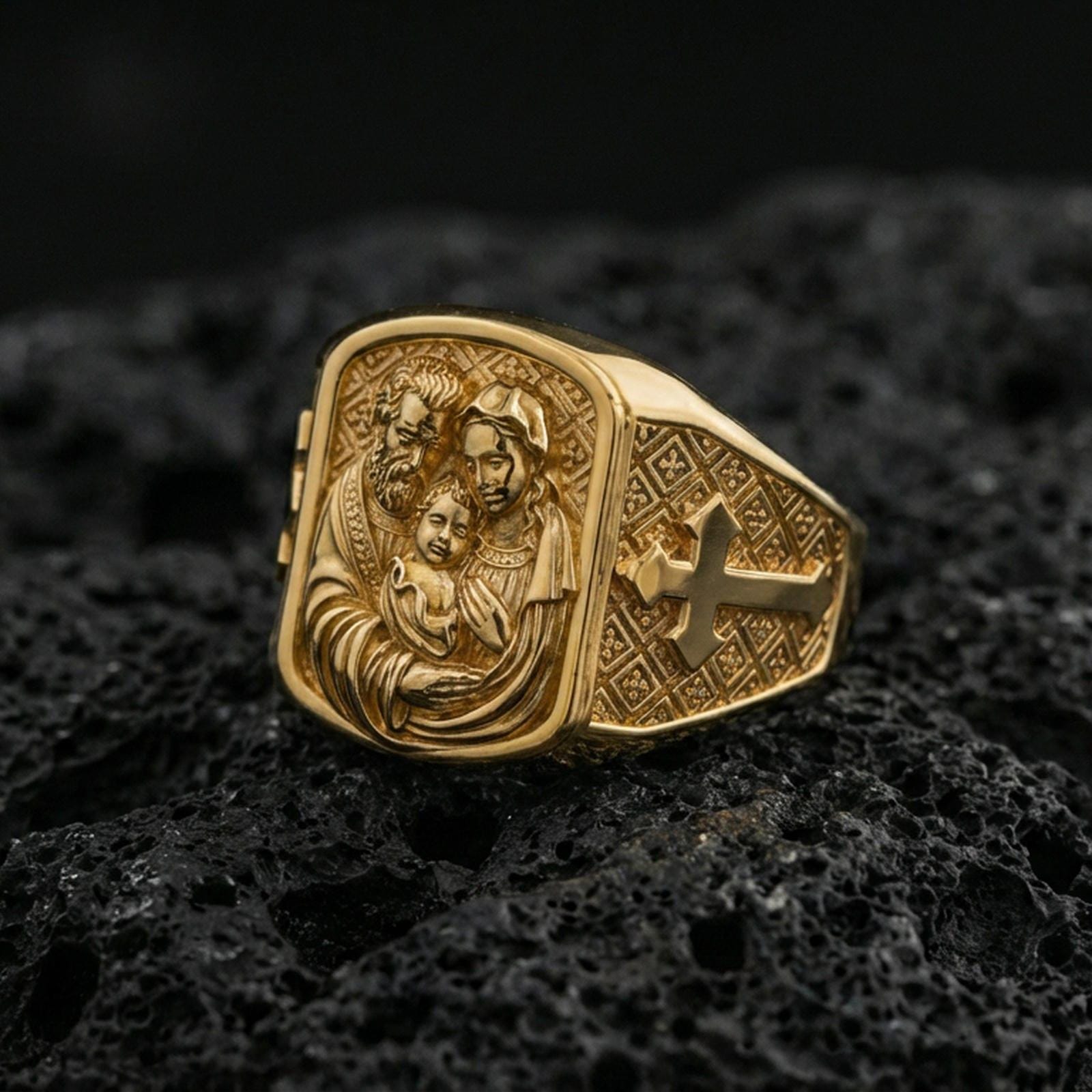 Gold plated Holy Family ring on dark volcanic rock, Mary Joseph and Jesus relief with cross motif band