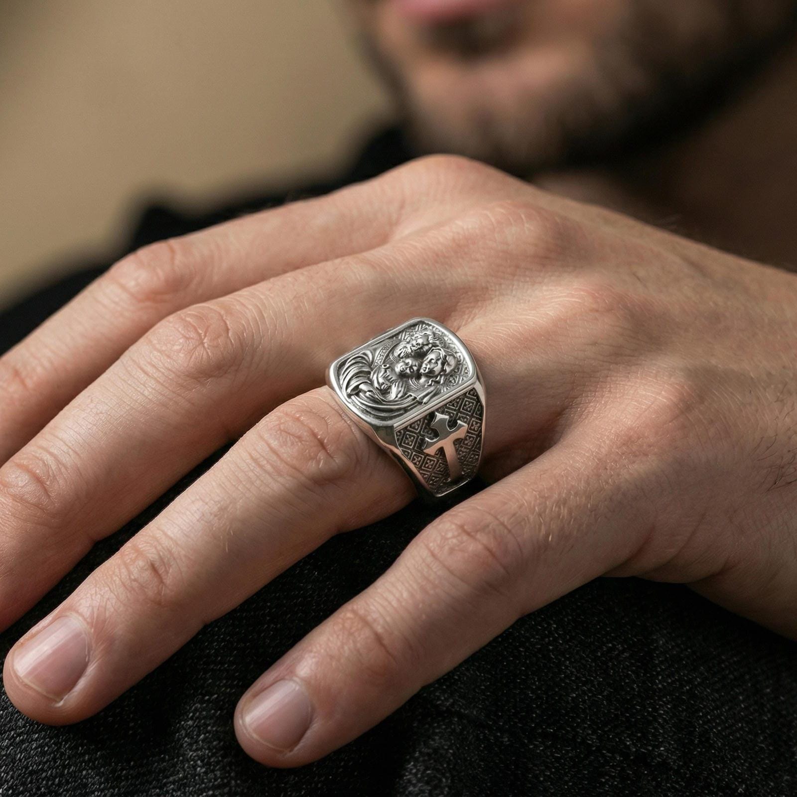 Polished silver Holy Family signet ring worn on finger, family portrait engraving and cross side panel