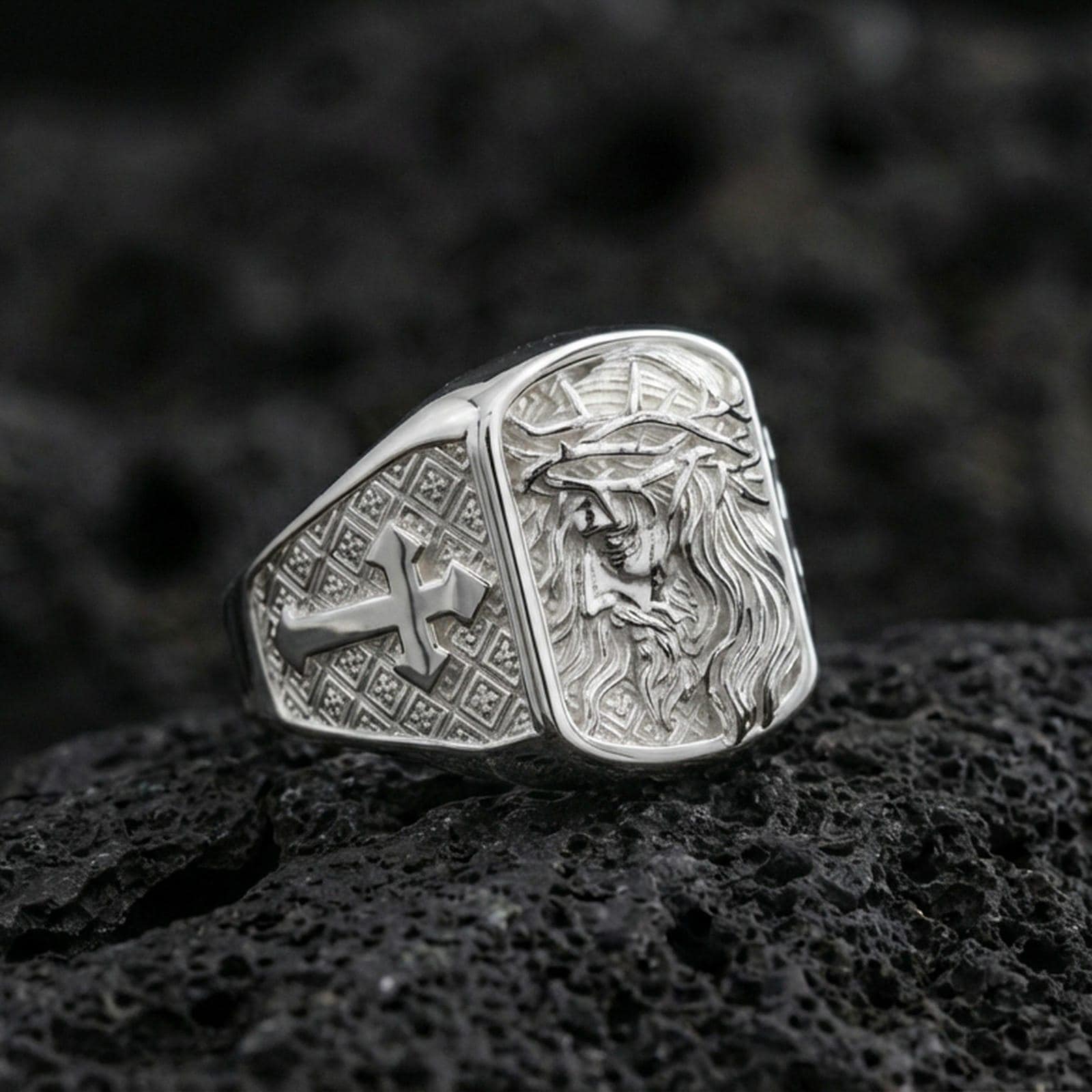 Polished silver Jesus of Nazareth signet ring on porous volcanic stone, detailed Christ portrait and cross band