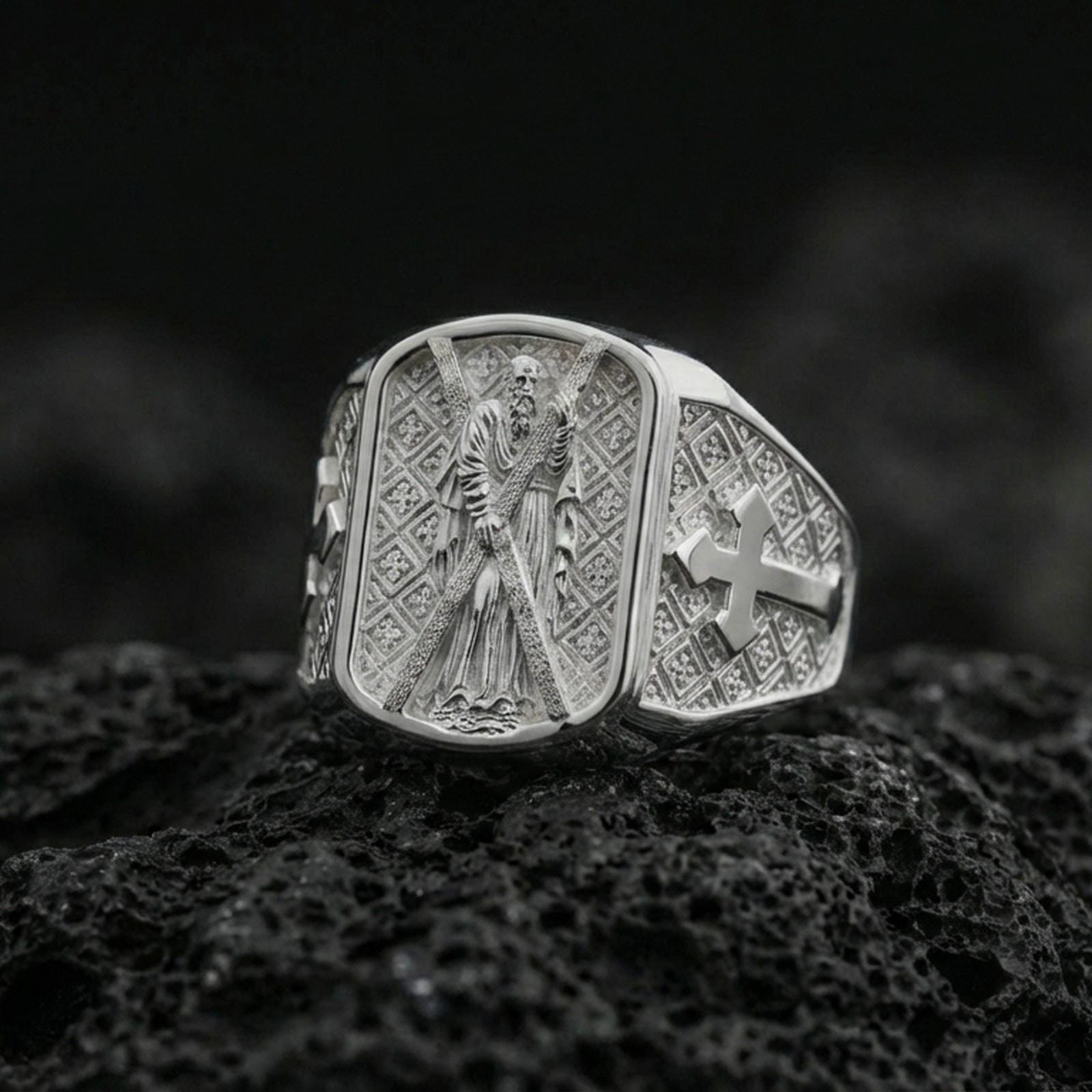Polished silver Saint Andrew signet ring on porous volcanic stone, detailed saint relief with cross side design