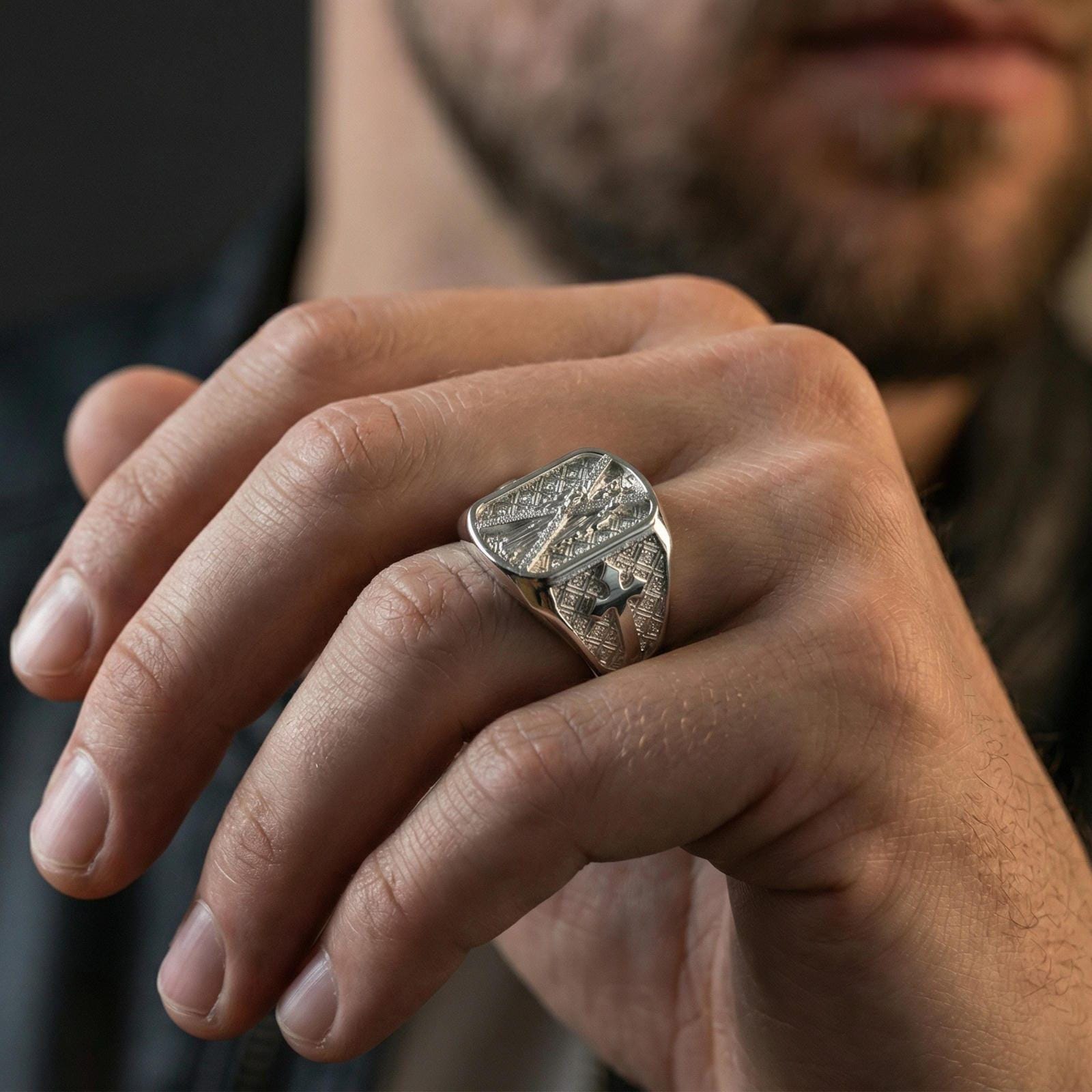 Polished silver Saint Andrew signet ring worn on finger, detailed saint relief with cross side design