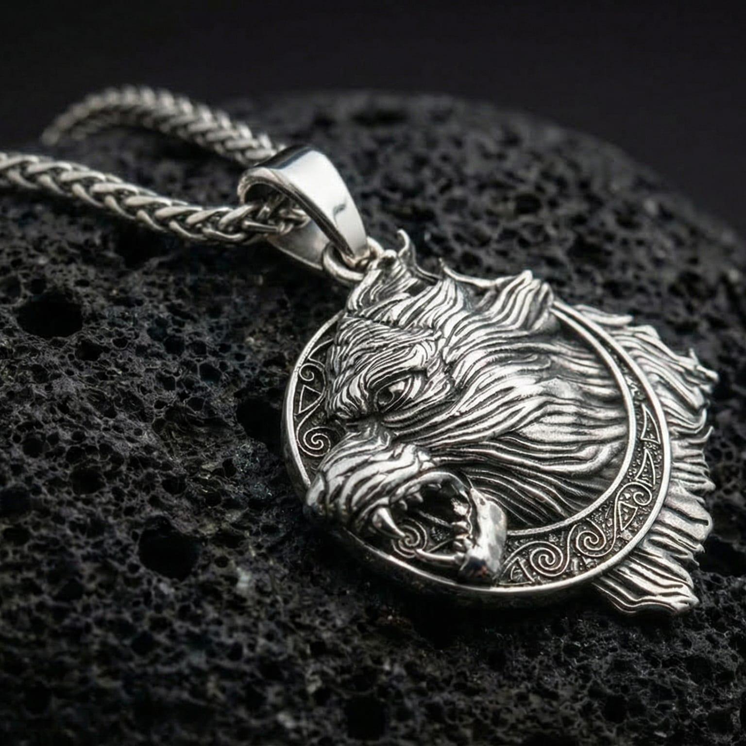 Polished silver Norse wolf Fenrir pendant displayed on volcanic stone background with sharp carved fur texture