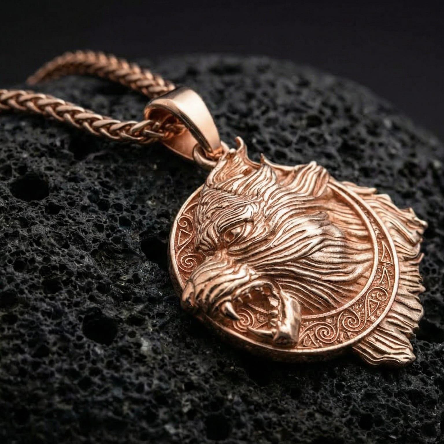 Rose gold plated Fenrir wolf pendant necklace presented on volcanic rock surface with bold Nordic myth aesthetic