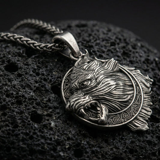 Oxidized Fenrir wolf pendant necklace photographed on volcanic rock with detailed Norse beast relief and runic frame