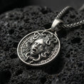 Load image into Gallery viewer, Oxidized Medusa necklace pendant photographed on volcanic rock with detailed snake hair relief and Greek key border
