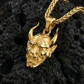 Load image into Gallery viewer, Gold plated oni mask pendant showcased on volcanic rock as a symbol of protection, courage, and warrior energy
