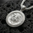 Load image into Gallery viewer, Polished silver Medusa Greek mythology pendant displayed on volcanic stone background highlighting detailed serpent hair engraving
