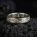 Load image into Gallery viewer, Polished silver Celtic knot band ring displayed on volcanic stone background highlighting smooth edges and intertwined design
