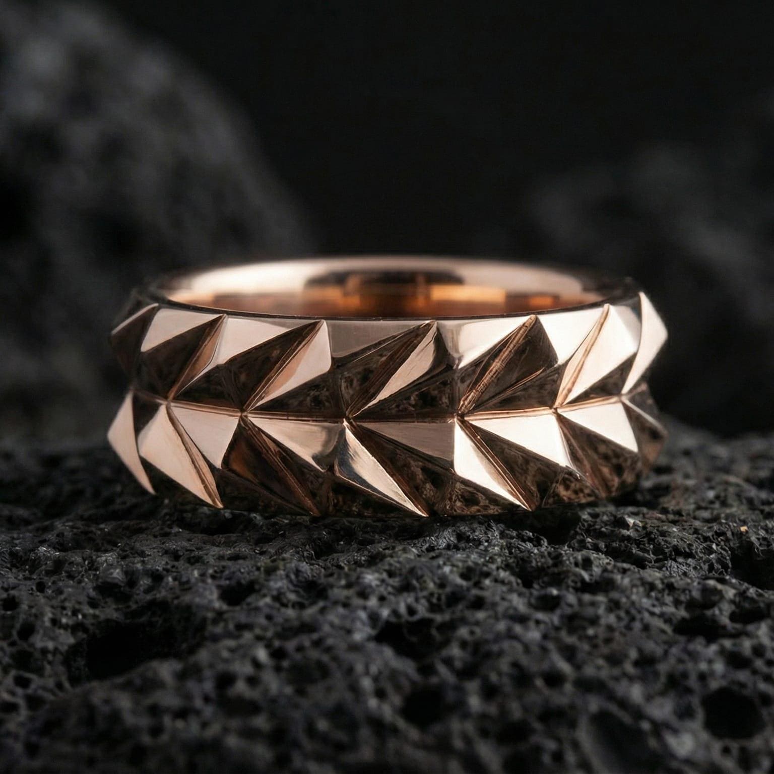 Rose gold plated faceted minimalist ring presented on volcanic rock surface with sculptural architecture and premium contemporary finish