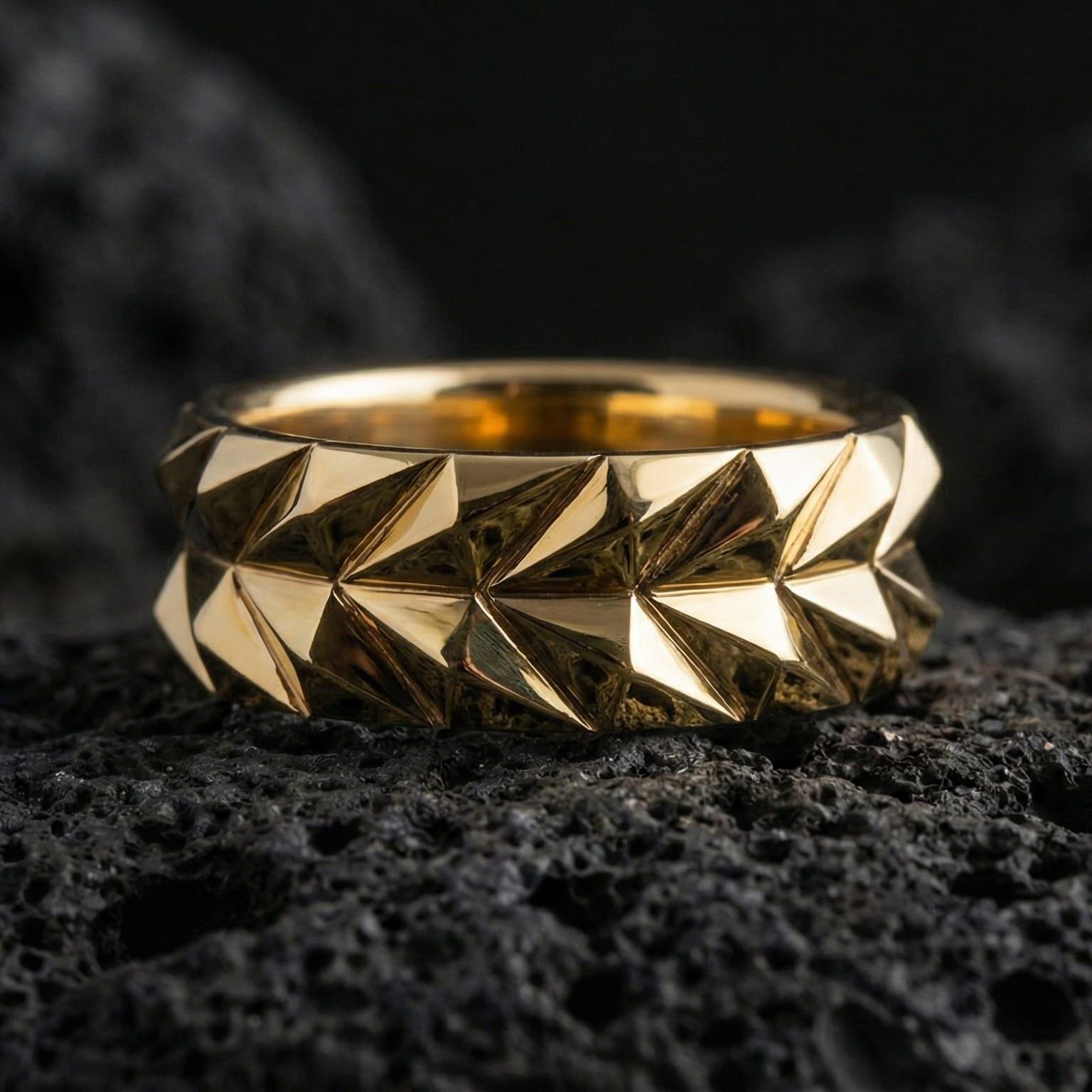 Gold plated angular geometric band ring showcased on volcanic rock as a symbol of strength, structure, and modern masculinity