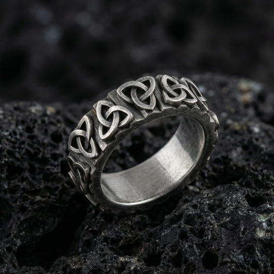 Oxidized sterling silver Celtic trinity knot band ring photographed on volcanic rock background