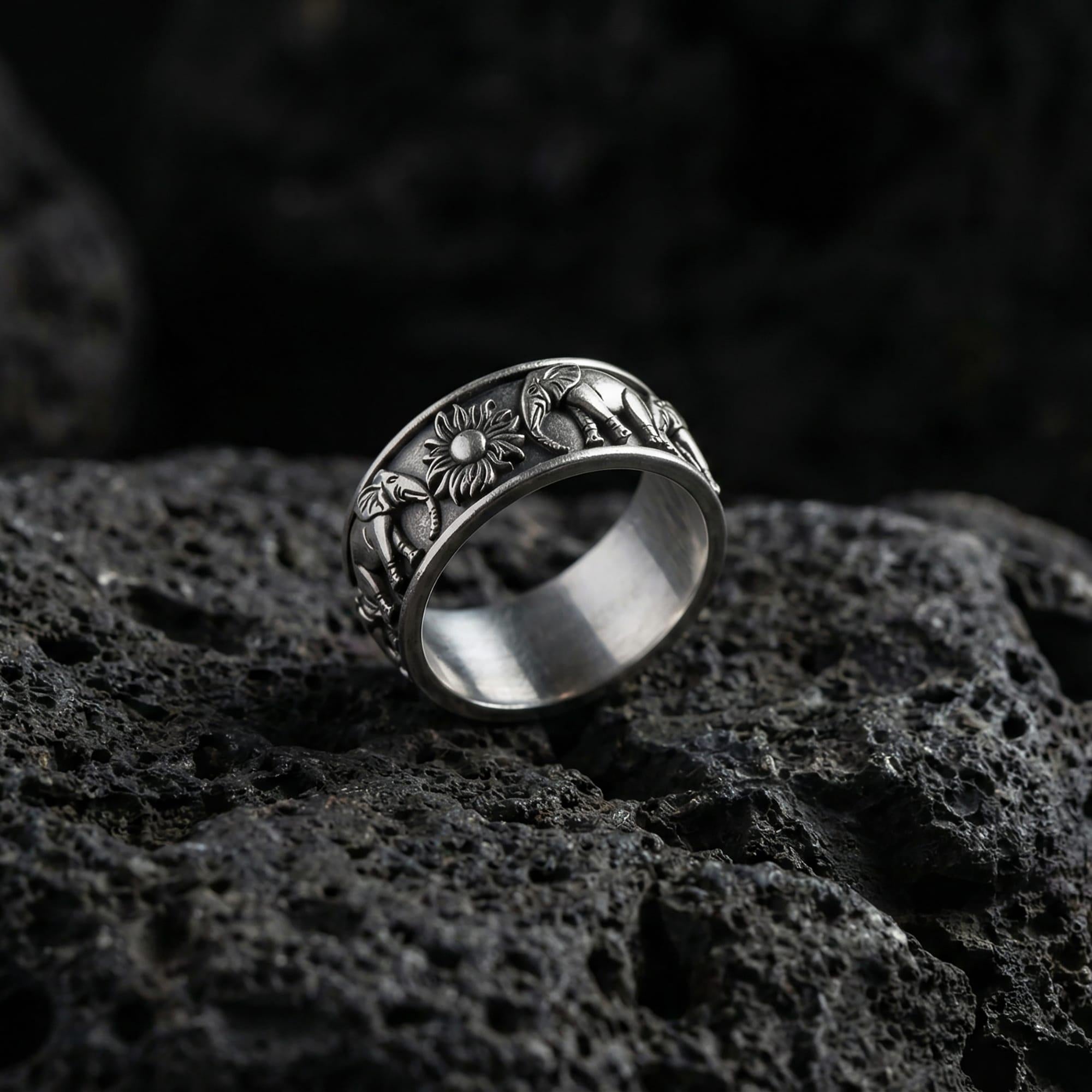 Oxidized geometric faceted band ring photographed on volcanic rock with sharp pyramid-cut texture and industrial masculine finish